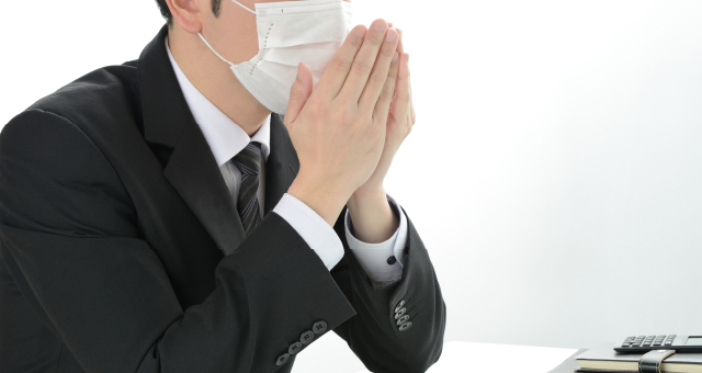 マスクをつけながら咳をしている男性イメージ